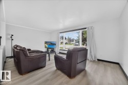 Bright living space featuring a large picture window, light wood-finish flooring, white walls, and white trim - 