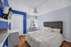 Bright bedroom featuring wood-finish flooring, a window with white curtains, a white bi-fold closet door, and a ceiling fan - 