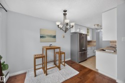 Kitchen and dining area featuring wood-finish flooring, a contemporary chandelier, white cabinetry, stainless steel appliances, and a tiled backsplash - 