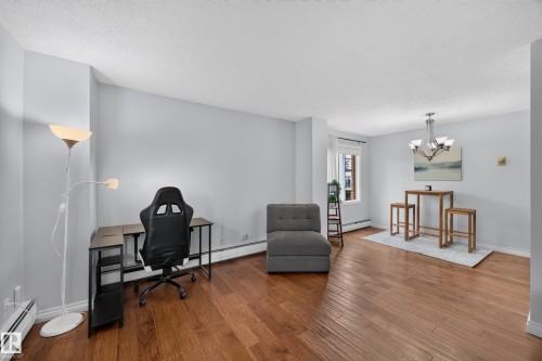 Open-concept room featuring wood-finish flooring, light-colored walls, and a window with natural light - #602 9725 106 St Nw, Edmonton, AB 