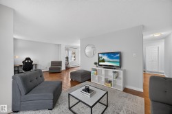 Open concept living area with wood-finish flooring, light grey wall paint, and white trim - 