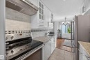 Kitchen featuring a stainless steel electric range, a mosaic tile backsplash with decorative border, white cabinetry, and granite countertops - #602 9725 106 St Nw, Edmonton, AB 