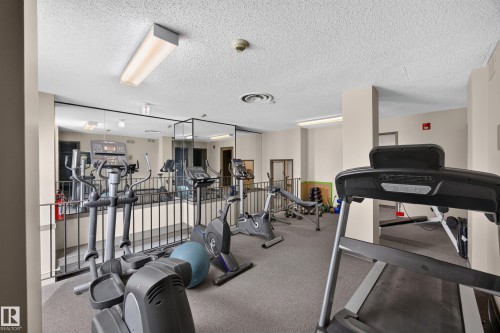 Fitness room featuring carpet flooring, mirrored wall, and recessed lighting - #602 9725 106 St Nw, Edmonton, AB 