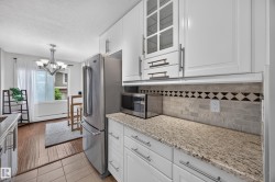 Kitchen featuring white cabinetry, granite-finish countertops, and a subway tile backsplash with decorative accents - 
