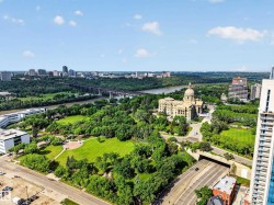 Expansive cityscape featuring a river, bridge, and prominent domed building surrounded by lush green parks - 