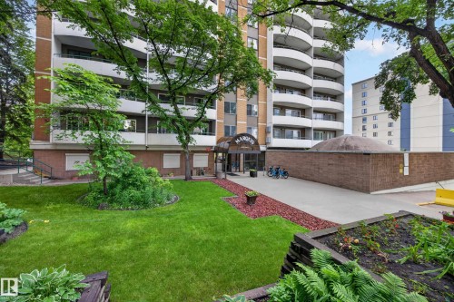 Multi-story building featuring a brick and light-colored facade, curved balconies, and a covered entrance with "MARQUIS" signage - #602 9725 106 St Nw, Edmonton, AB 