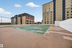 Rooftop recreation area featuring a multi-sport court with perimeter fencing and a surrounding paved surface - 