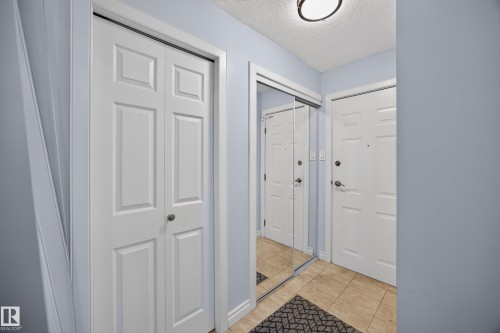 Entryway featuring light blue walls, tan tiled flooring, and a flush mount ceiling light - #602 9725 106 St Nw, Edmonton, AB 