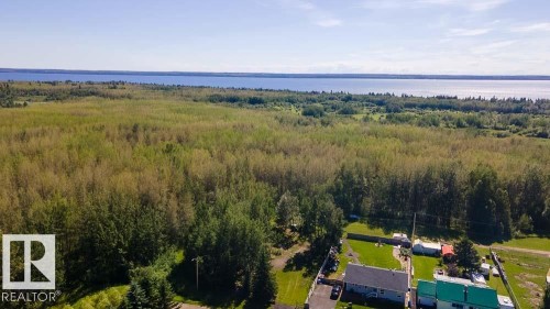 Expansive wooded landscape with visible waterfront in the distance - 4701 34 St., Rural Wetaskiwin County, AB 