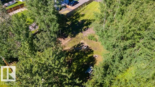 Expansive treed lot featuring a clearing with a fire pit, mature deciduous trees, and a wooden picnic table - 4701 34 St., Rural Wetaskiwin County, AB 