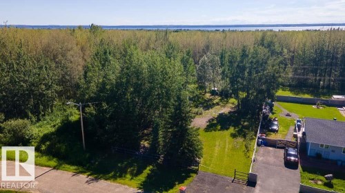 Extensive treed landscape featuring a cleared building site, paved driveway, and established residential property - 4701 34 St., Rural Wetaskiwin County, AB 