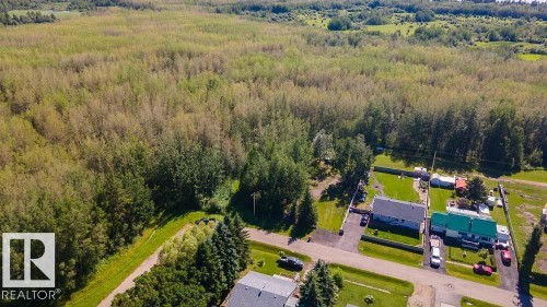 Expansive property featuring a dense treeline, cleared land, and open green spaces - 4701 34 St., Rural Wetaskiwin County, AB 