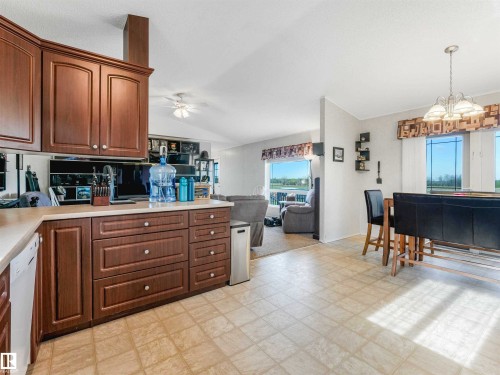 Spacious kitchen featuring warm wood cabinetry, light-toned countertops, and tile-finish flooring - 57016 Range Road 13, Rural Barrhead County, AB - Indoor Photo Showing Kitchen