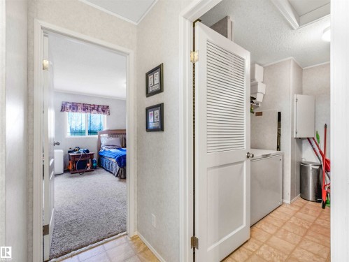 Louvered bi-fold door revealing a dedicated laundry area with tiled flooring and wall-mounted cabinetry - 57016 Range Road 13, Rural Barrhead County, AB - Indoor