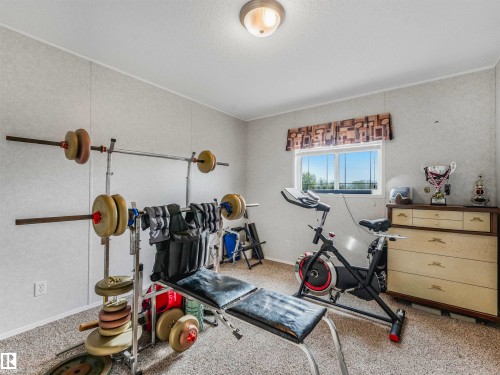 Carpeted room with a window providing natural light, featuring a ceiling-mounted light fixture - 57016 Range Road 13, Rural Barrhead County, AB - Indoor Photo Showing Gym Room