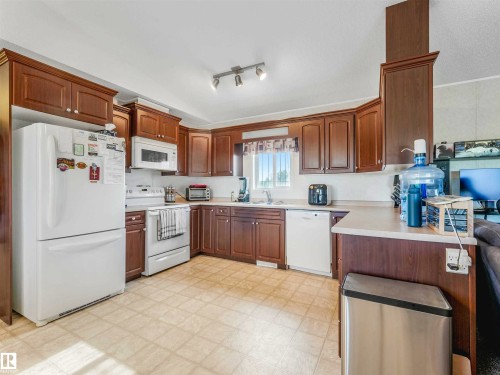 Kitchen featuring wood cabinetry, white appliances, track lighting, and a neutral countertop - 57016 Range Road 13, Rural Barrhead County, AB - Indoor Photo Showing Kitchen