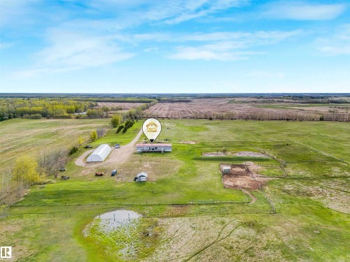 Expansive rural property featuring a primary residence with a surrounding lawn, a large greenhouse structure, a storage shed, and fenced pasture areas - 57016 Range Road 13, Rural Barrhead County, AB - Outdoor With View