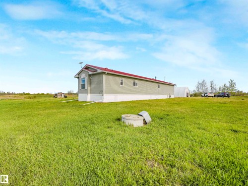 Expansive green space featuring a long-form residence with light green siding and a red roof - 57016 Range Road 13, Rural Barrhead County, AB - Outdoor