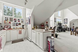 Kitchen area featuring white cabinetry, light-toned flooring, and a large window with grid panes - 