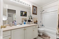 Bathroom featuring a built-in vanity with a light-colored countertop, an undermount sink, and white cabinetry - 