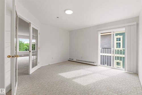 Bright room with light-colored patterned carpeting and white walls - #201 14 Mission Av, St. Albert, AB - Indoor Photo Showing Other Room