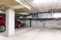 Concrete parking structure with exposed concrete ceiling, support columns, and industrial ductwork - 