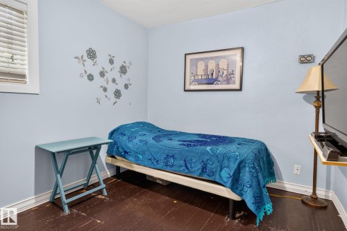 Room featuring light blue walls, dark wood-finish flooring, and a single window with blinds - 12703 122 Street Nw, Edmonton, AB 