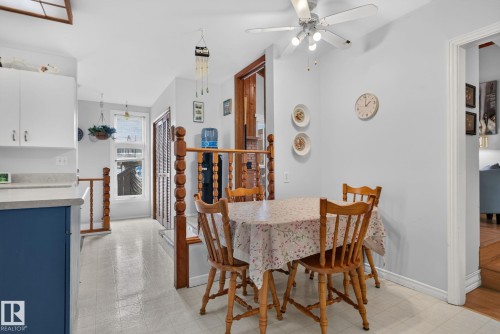 Dining area featuring a ceiling fan with integrated lighting, a half-wall with wooden balusters, and light-toned flooring - 12703 122 Street Nw, Edmonton, AB 