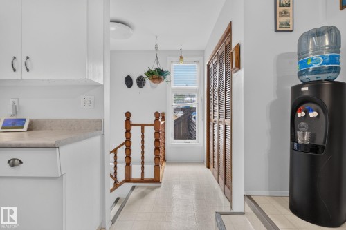Upper-level landing featuring a wood spindle railing, two-panel wood louvered closet doors, and light-toned flooring - 12703 122 Street Nw, Edmonton, AB 