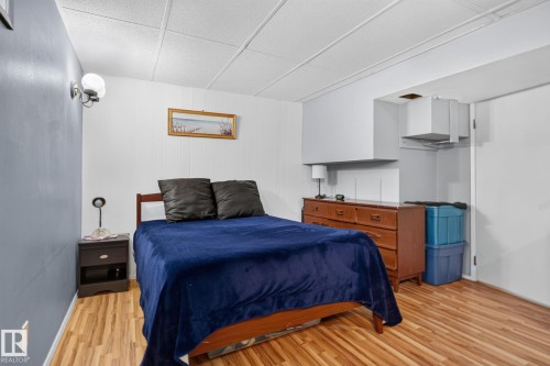Room featuring wood-finish flooring, white panel walls, and a drop ceiling - 12703 122 Street Nw, Edmonton, AB 