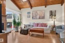 Living area featuring wood-finish flooring, a brick fireplace surround, vaulted wood-beamed ceilings, and a skylight - 12703 122 Street Nw, Edmonton, AB 