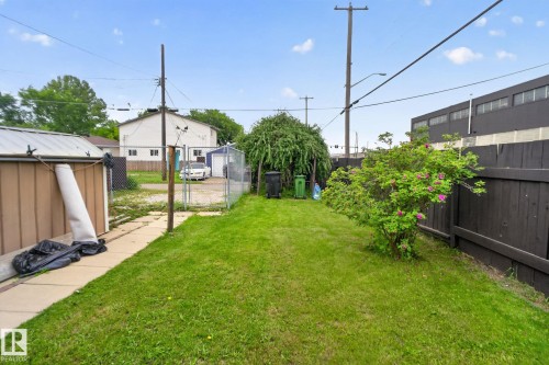 Expansive grassy yard featuring a chain-link fence, a brown utility shed with a metal roof, and a dark stained privacy fence - 12703 122 Street Nw, Edmonton, AB 