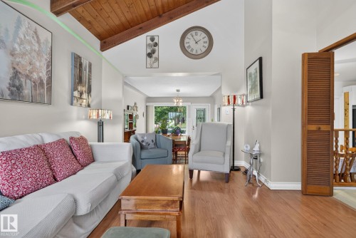 Living area with vaulted wood-beamed ceiling, wood-finish flooring, and a louvered bi-fold door - 12703 122 Street Nw, Edmonton, AB 