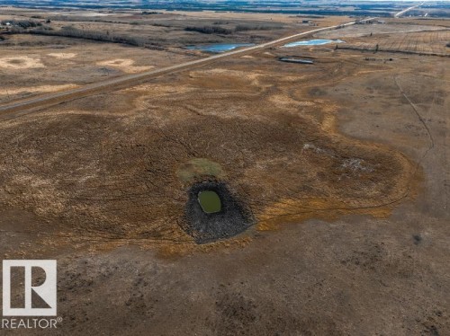 Expansive land parcel featuring open fields, an established road, and multiple natural water features including a central pond - 0 Ne-3-56-12-W4 Northeast, Rural Two Hills County, AB 