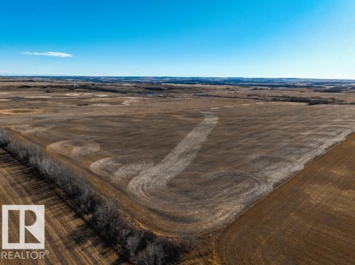 Expansive agricultural land featuring cultivated fields, a distinct treeline bordering the property, and distant natural terrain under a clear sky - 0 Ne-3-56-12-W4 Northeast, Rural Two Hills County, AB 