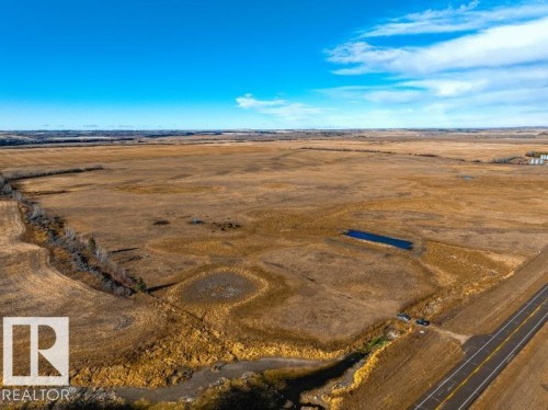 Expansive land offering a clear blue sky, a pond, and direct road frontage - 0 Ne-3-56-12-W4 Northeast, Rural Two Hills County, AB 