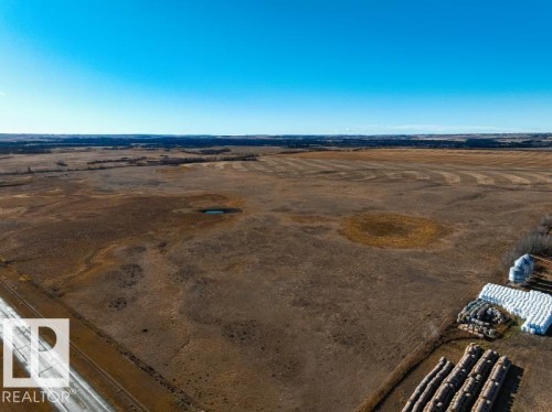 Expansive land parcel featuring a visible roadway, natural pond, and distant tree lines - 0 Ne-3-56-12-W4 Northeast, Rural Two Hills County, AB 