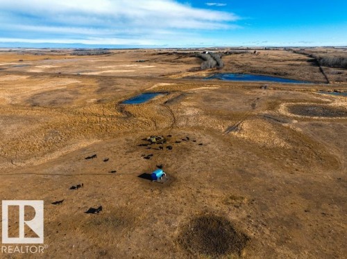 Expansive agricultural land featuring a natural pond, a blue structure, and scattered trees on the horizon - 0 Ne-3-56-12-W4 Northeast, Rural Two Hills County, AB 