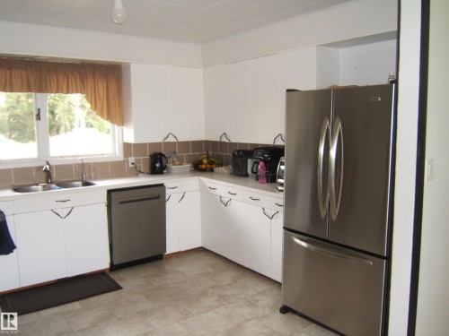 Kitchen featuring white cabinetry, a double basin stainless steel sink, a stainless steel dishwasher, a stainless steel French door refrigerator, and a tiled backsplash - 543016 Rng Rd 122, Rural Two Hills County, AB - Indoor Photo Showing Kitchen With Double Sink