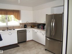 Kitchen featuring white cabinetry, a double basin stainless steel sink, a stainless steel dishwasher, a stainless steel French door refrigerator, and a tiled backsplash - 