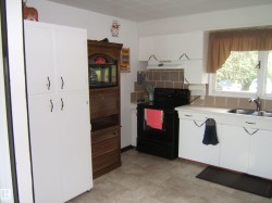 Kitchen featuring white cabinetry, a black electric range, a double basin sink, neutral tile flooring, and a tiled backsplash - 