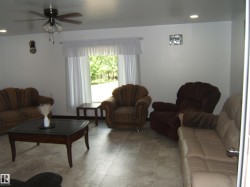 Spacious living area featuring light-toned tile flooring, recessed ceiling lighting, and a ceiling fan with integrated illumination - 