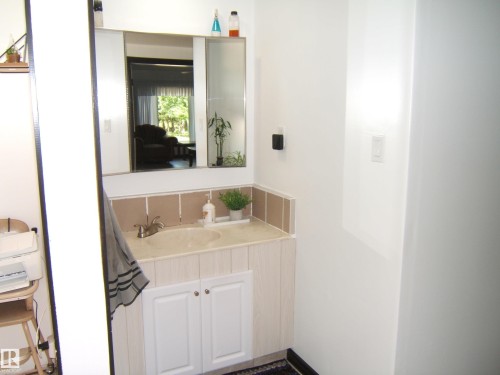 Bathroom vanity with integrated sink, chrome faucet, and white cabinet storage - 543016 Rng Rd 122, Rural Two Hills County, AB - Indoor