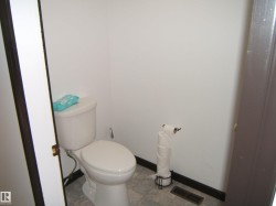 White porcelain toilet with a dark baseboard trim and light-colored floor tiling - 