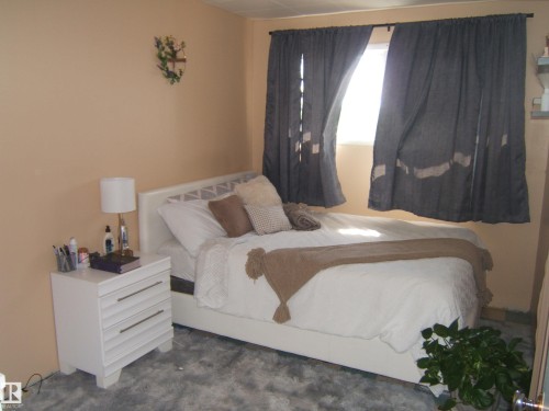 Room featuring neutral wall tones, window with dark drapes, and a decorative wall hanging - 543016 Rng Rd 122, Rural Two Hills County, AB - Indoor Photo Showing Bedroom