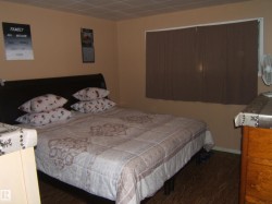 Bedroom featuring wood-finish flooring, neutral wall tones, and a window with blinds - 