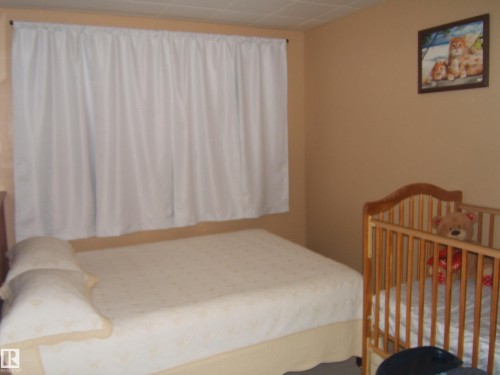 Bedroom featuring light beige wall paint, a window with white curtains, and a textured ceiling - 543016 Rng Rd 122, Rural Two Hills County, AB - Indoor Photo Showing Bedroom