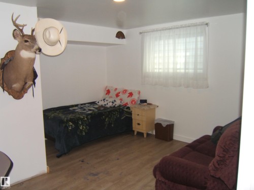 Room with wood-finish flooring, white walls, and a window with sheer white curtains - 543016 Rng Rd 122, Rural Two Hills County, AB - Indoor Photo Showing Other Room