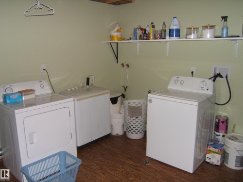Dedicated laundry area featuring wood-finish flooring, light green walls, and built-in shelving for storage - 543016 Rng Rd 122, Rural Two Hills County, AB - Indoor Photo Showing Laundry Room