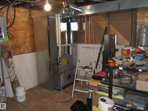 Utility area featuring a furnace system with associated ductwork and piping, an exposed subfloor, exposed ceiling joists, and a partial plywood wall - 543016 Rng Rd 122, Rural Two Hills County, AB - Indoor Photo Showing Basement
